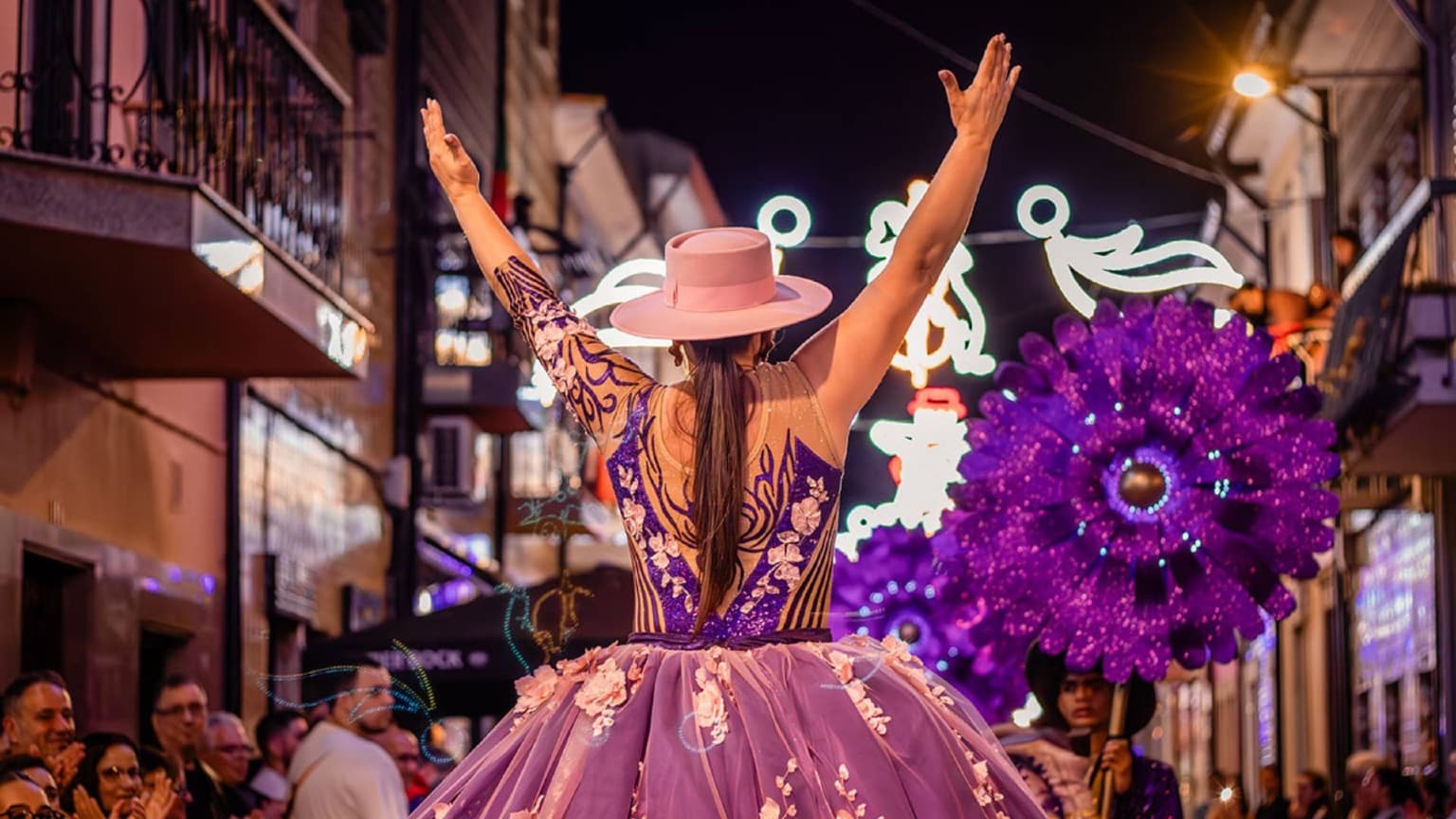 Dancer in a colorful dress performing at a night parade during the Festas de São Pedro in Afurada, near Porto, Portugal.