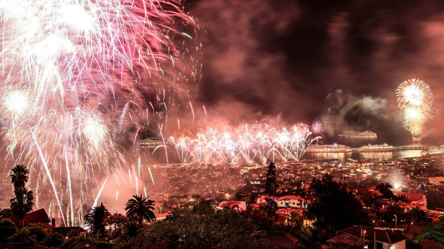 Fuegos artificiales sobre la bahía de Funchal durante la Nochevieja en Madeira, con cruceros y el perfil iluminado de la ciudad.
