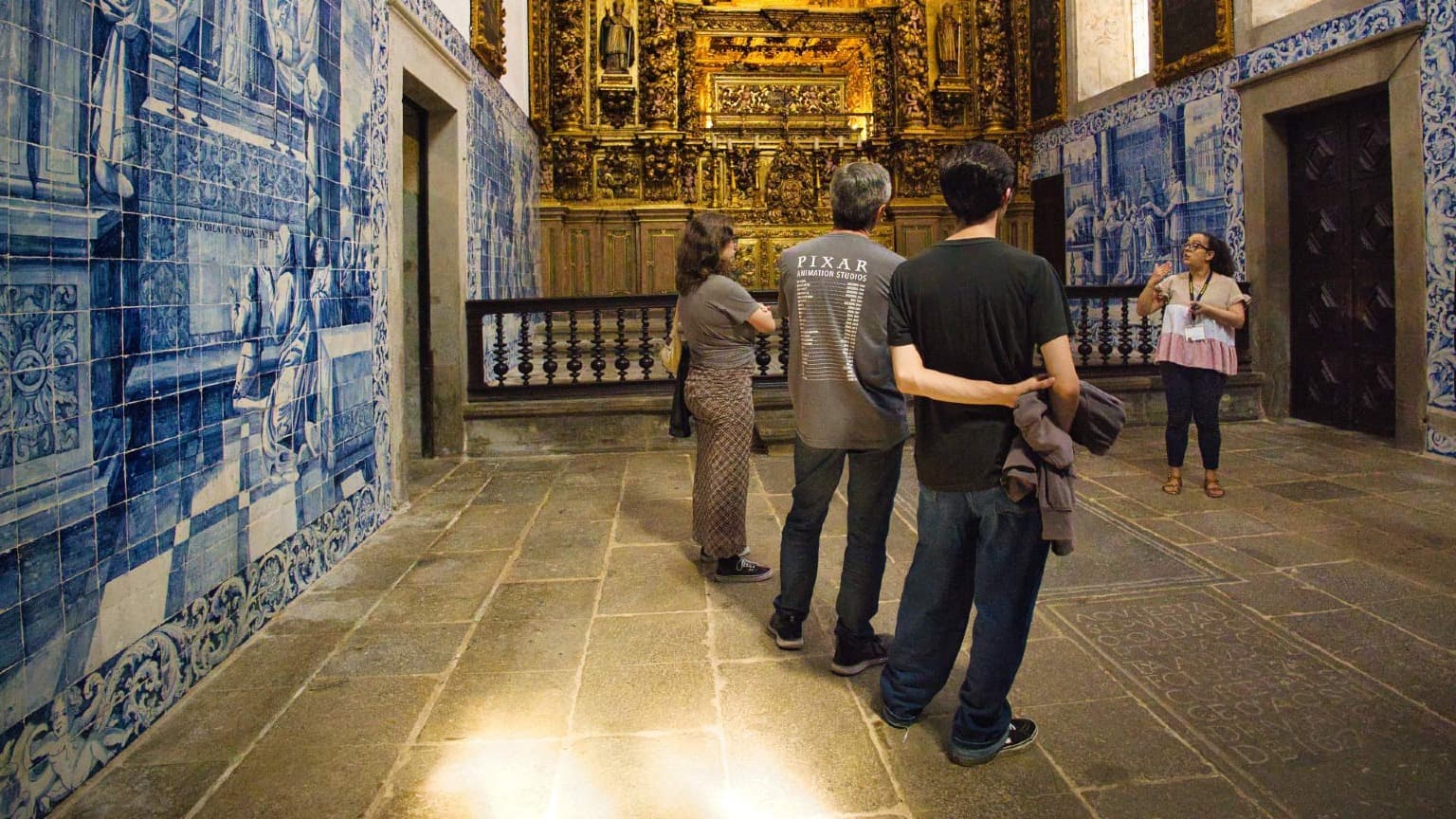 Visitantes a explorar o interior da Catedral de Braga durante uma visita guiada, com azulejos e detalhes barrocos
