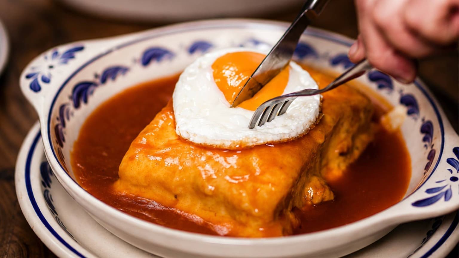 Traditional Francesinha at Yuko Tavern in Porto served with melted cheese, fried egg, and rich sauce
