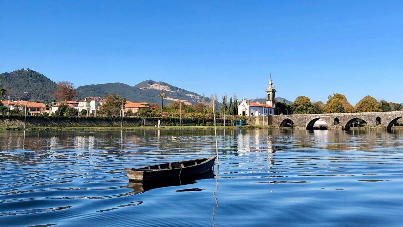 Vue panoramique de Ponte de Lima avec son pont médiéval en pierre, son église historique et ses montagnes en arrière-plan.