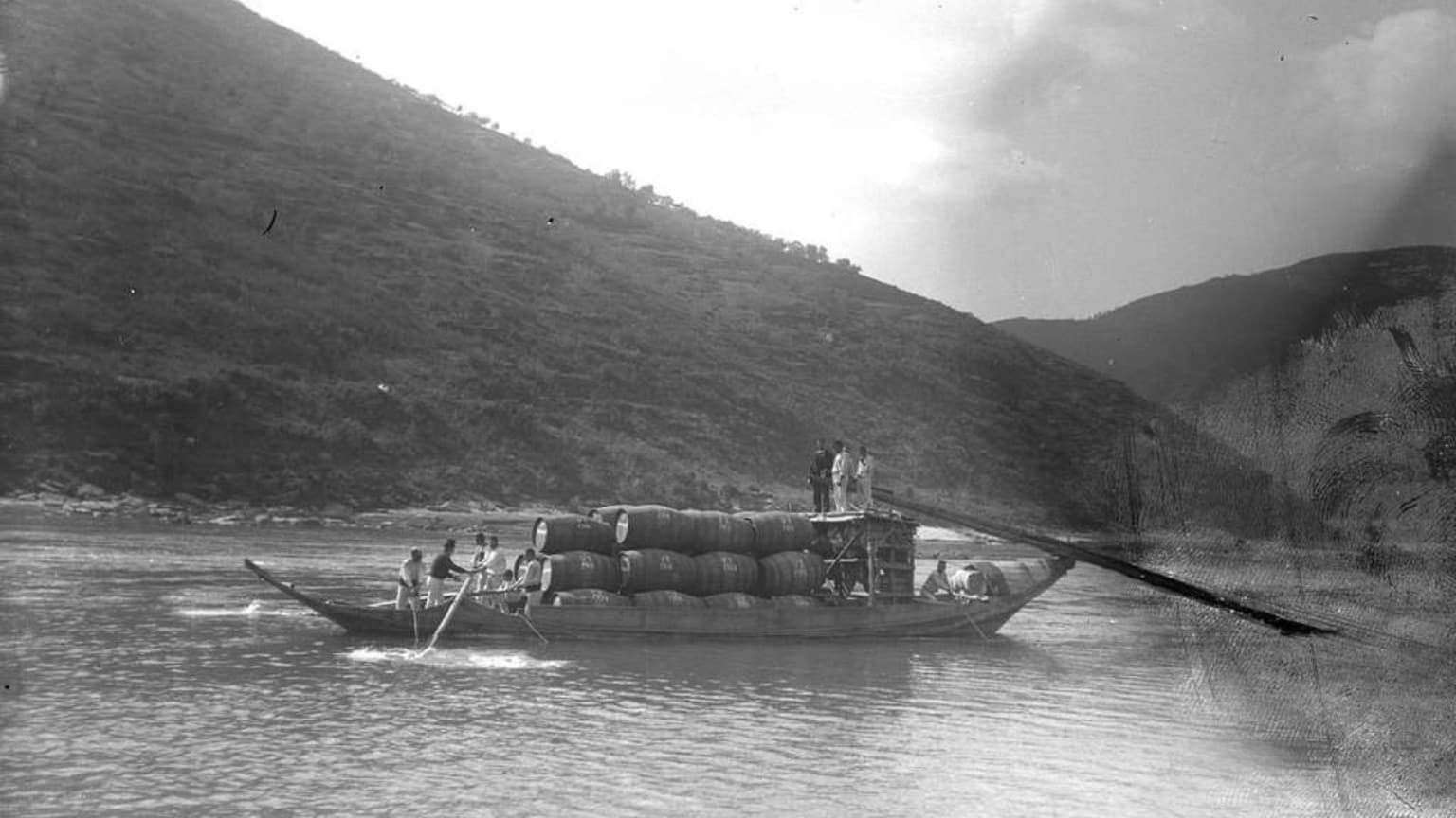 Bateau Rabelo historique naviguant sur le fleuve Douro avec des tonneaux de vin de Porto, illustrant le transport traditionnel du vin dans la vallée du Douro