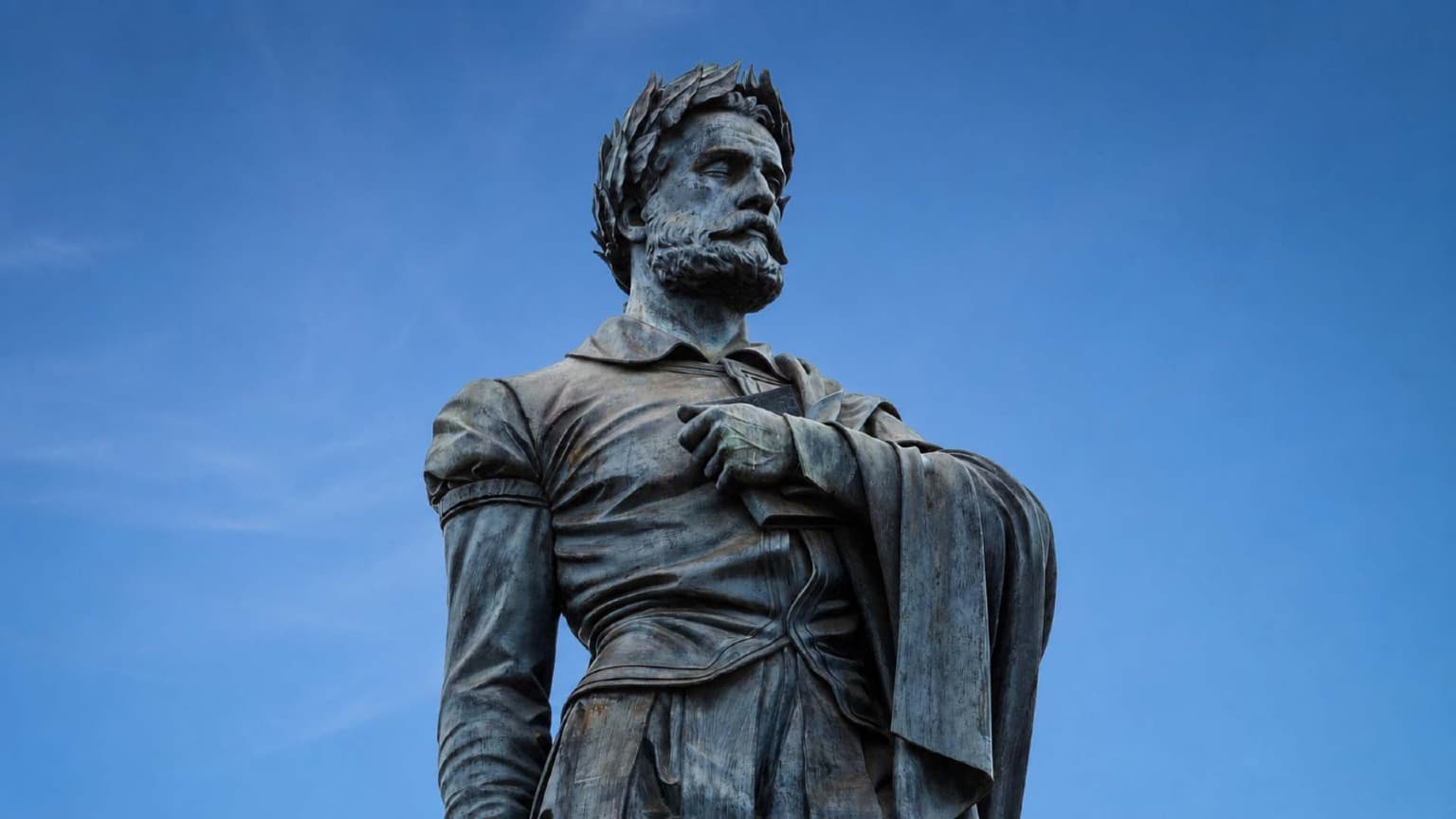 Estatua de Luís de Camões en Lisboa, Portugal, contra un cielo azul, símbolo de la literatura portuguesa y de las celebraciones del Día de Portugal el 10 de junio