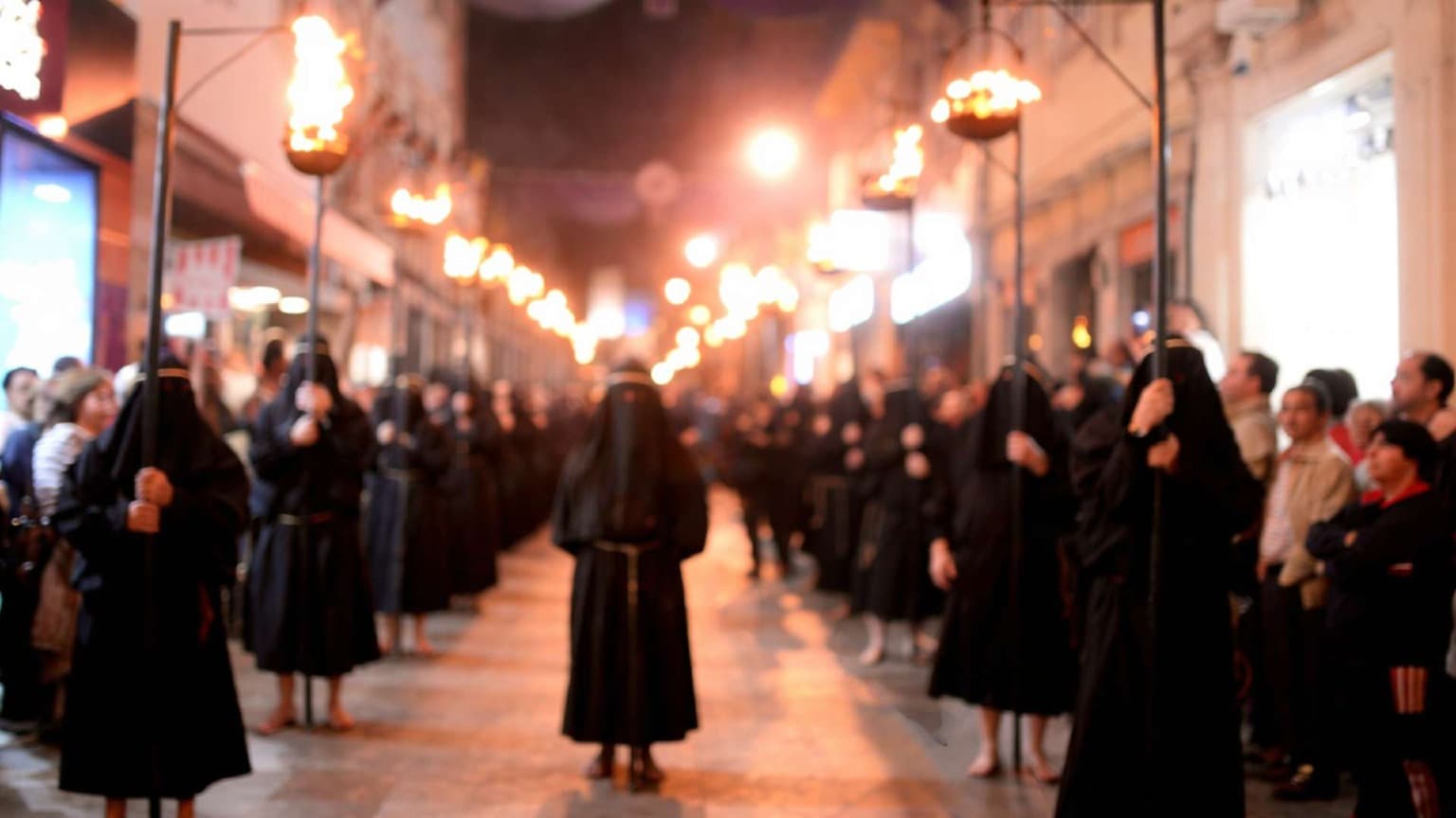 Procesión del Ecce Homo en Braga durante la Semana Santa, con participantes vestidos con túnicas negras tradicionales y portando antorchas