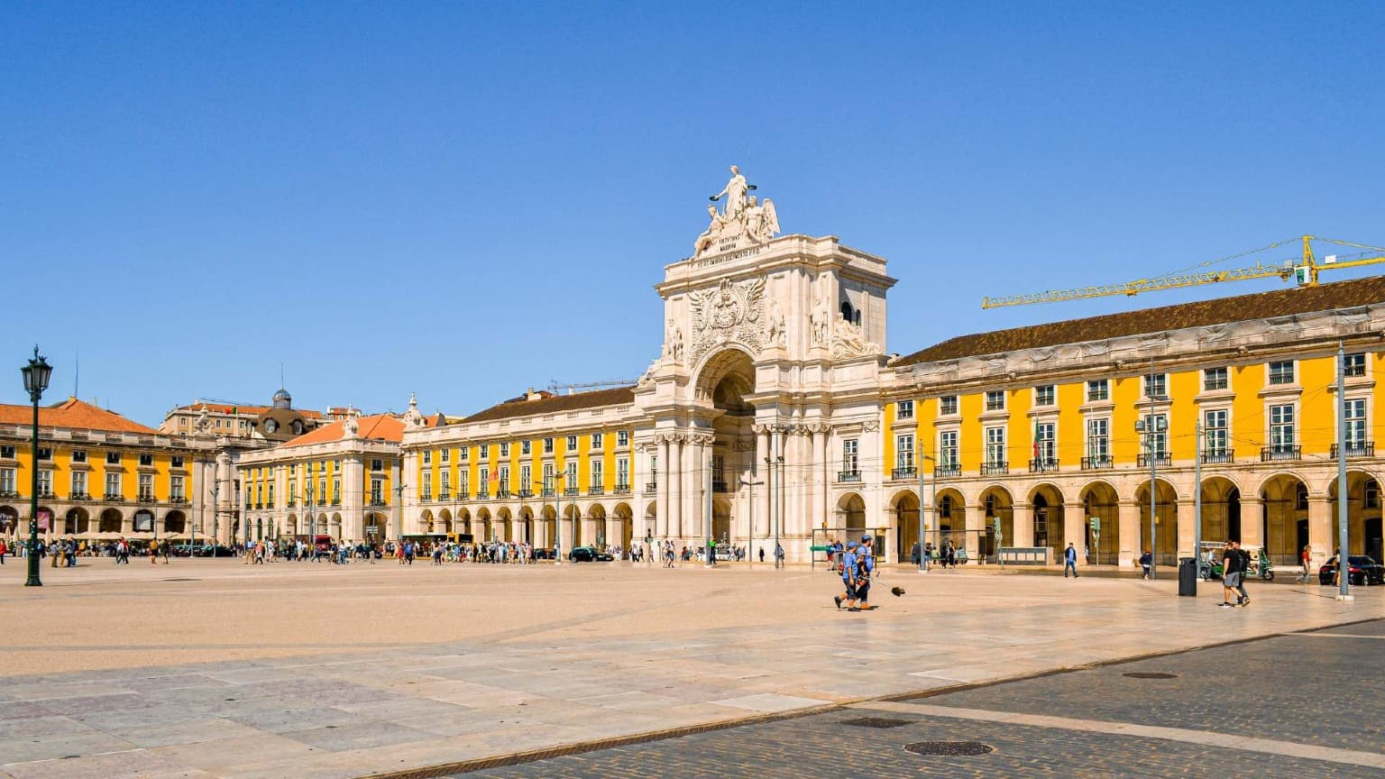 La plaza Praça do Comércio de Lisboa con el Arco da Rua Augusta y los edificios amarillos con arcadas en un día soleado.