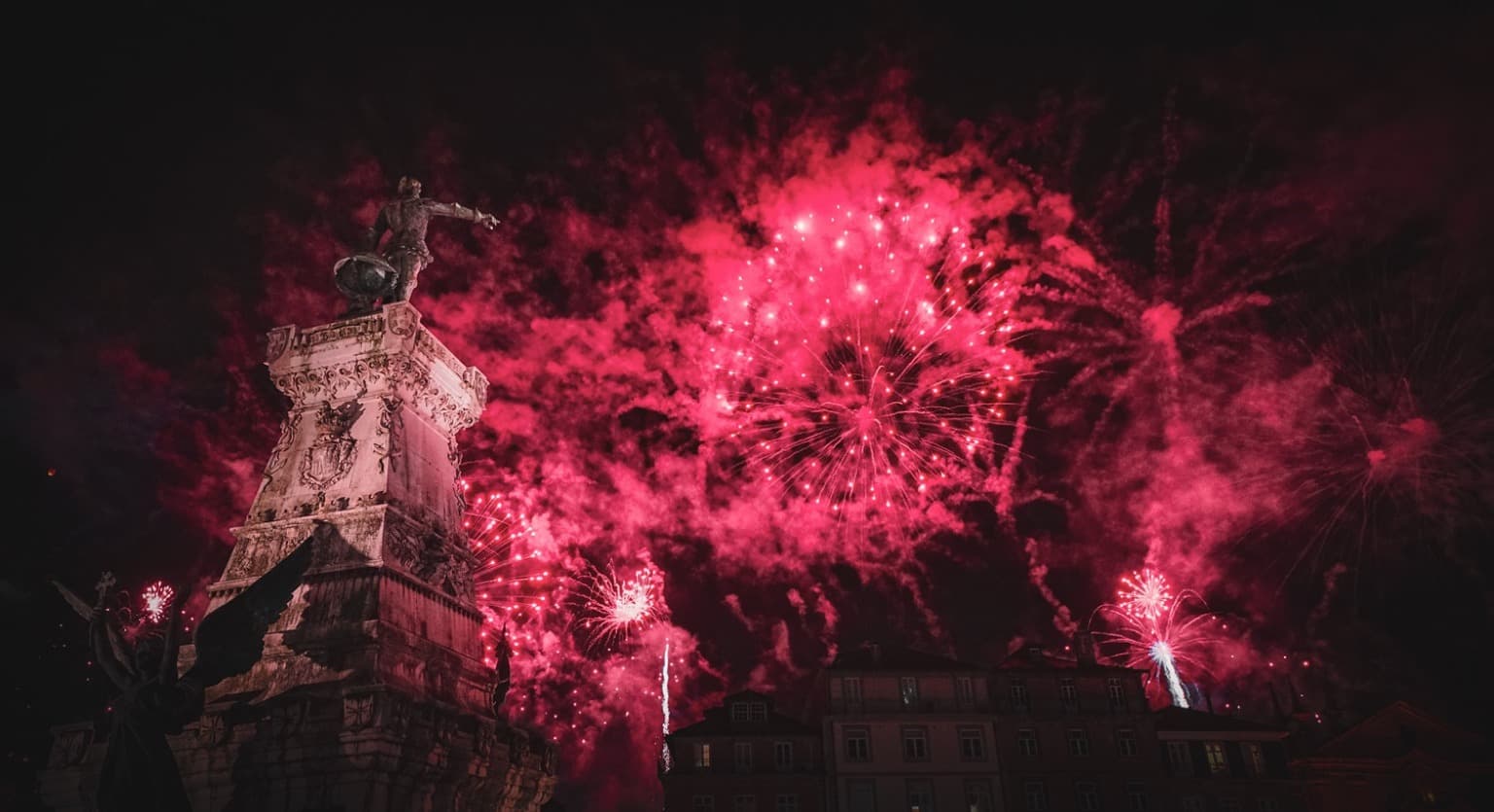 Vibrantes fuegos artificiales iluminando el cielo y reflejándose en el río Duero, celebrando la festividad de São João en Oporto.