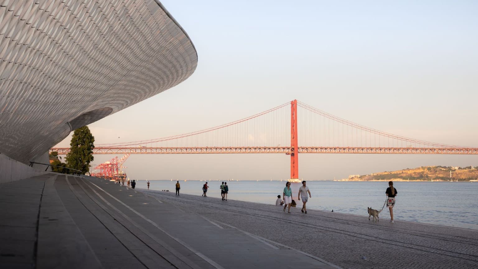 Pessoas a caminhar junto ao museu MAAT, ao longo do rio Tejo, em Lisboa