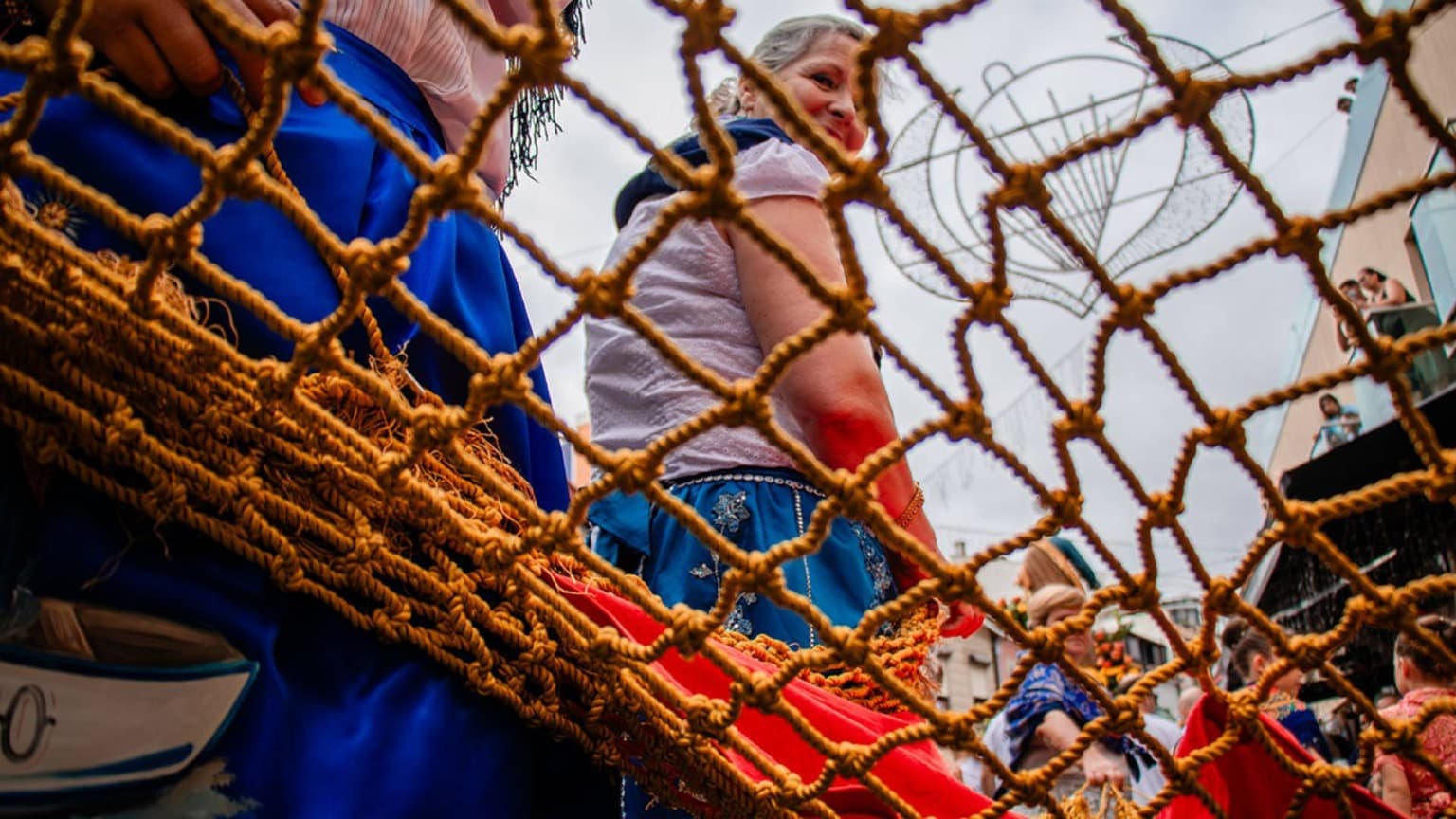 Mujeres con trajes tradicionales y redes de pesca en las Festas de São Pedro del pueblo pesquero de Afurada, en Vila Nova de Gaia.