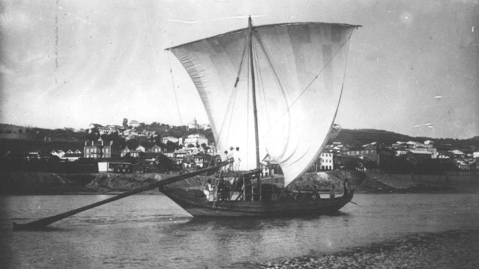 Barco tradicional Rabelo a navegar no rio Douro, perto do Porto, transportando barris de vinho do Porto no início do século XX