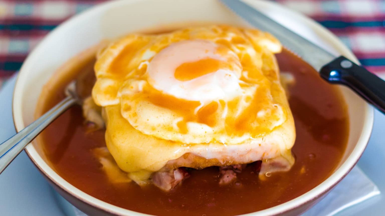 Francesinha traditionnelle servie avec du fromage fondu, une sauce généreuse et des frites à Porto