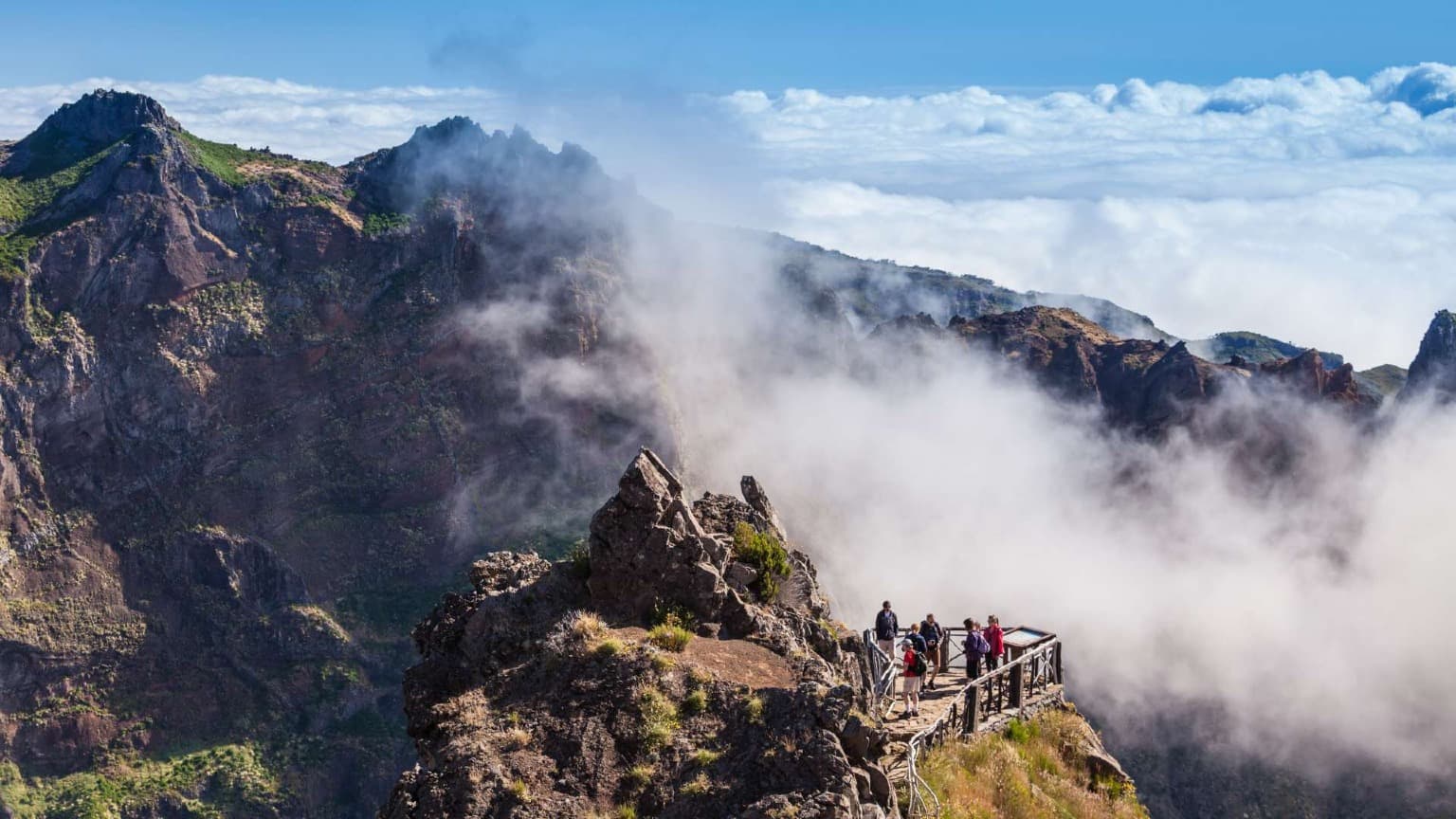 Hikers at the Ninho da Manta viewpoint on the Pico do Arieiro to Pico Ruivo trail, overlooking Madeira’s mountain peaks and cloud inversion.