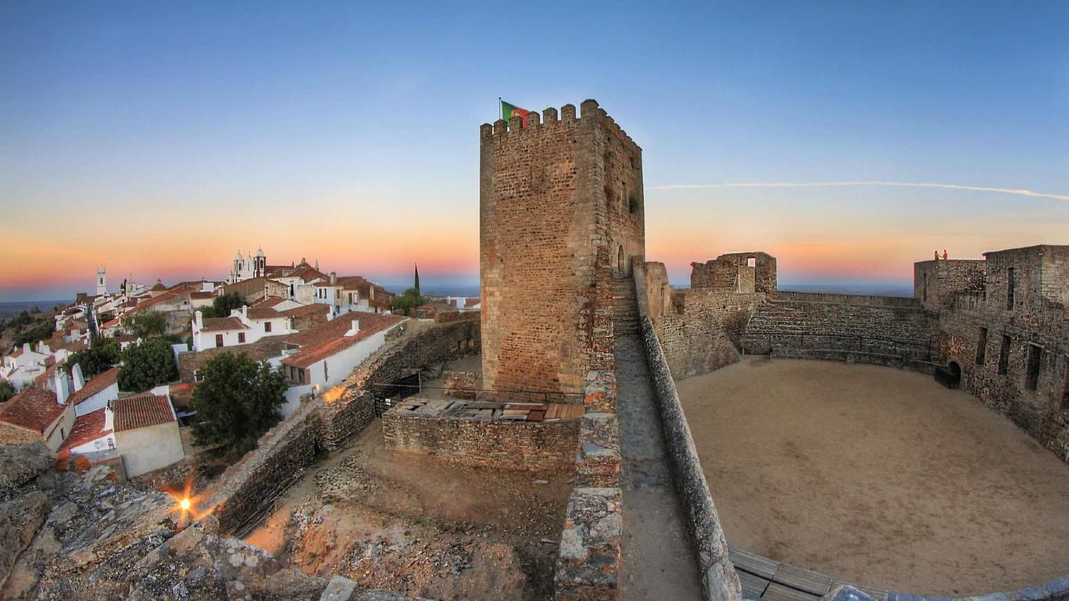 Vista del castillo de Monsaraz al atardecer y del pueblo encalado con vistas al lago Alqueva, en el Alentejo.