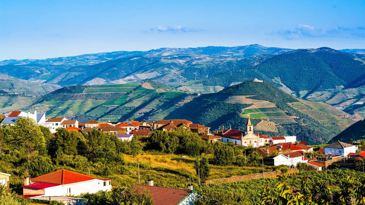 Provesende village in the Douro Valley with red-roofed houses overlooking vineyard terraces and mountain landscapes