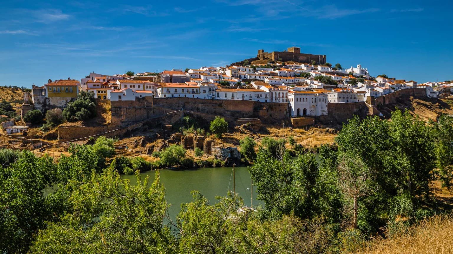 Vista ribereña de Mértola con su castillo en lo alto de la colina y sus casas blancas con vistas al río Guadiana.