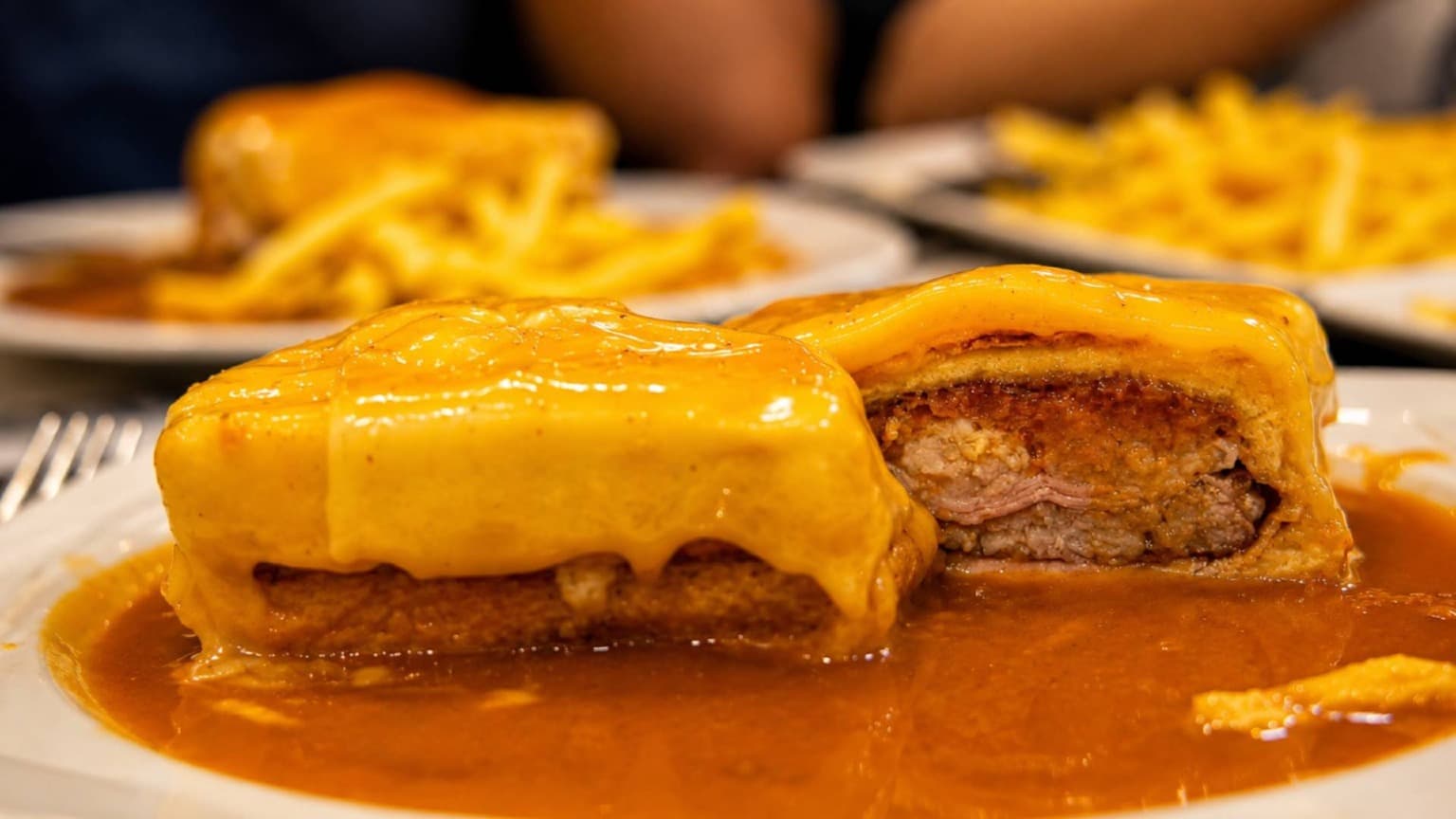 Francesinha served at O Afonso restaurant in Porto with crispy French fries and spicy meat-based sauce