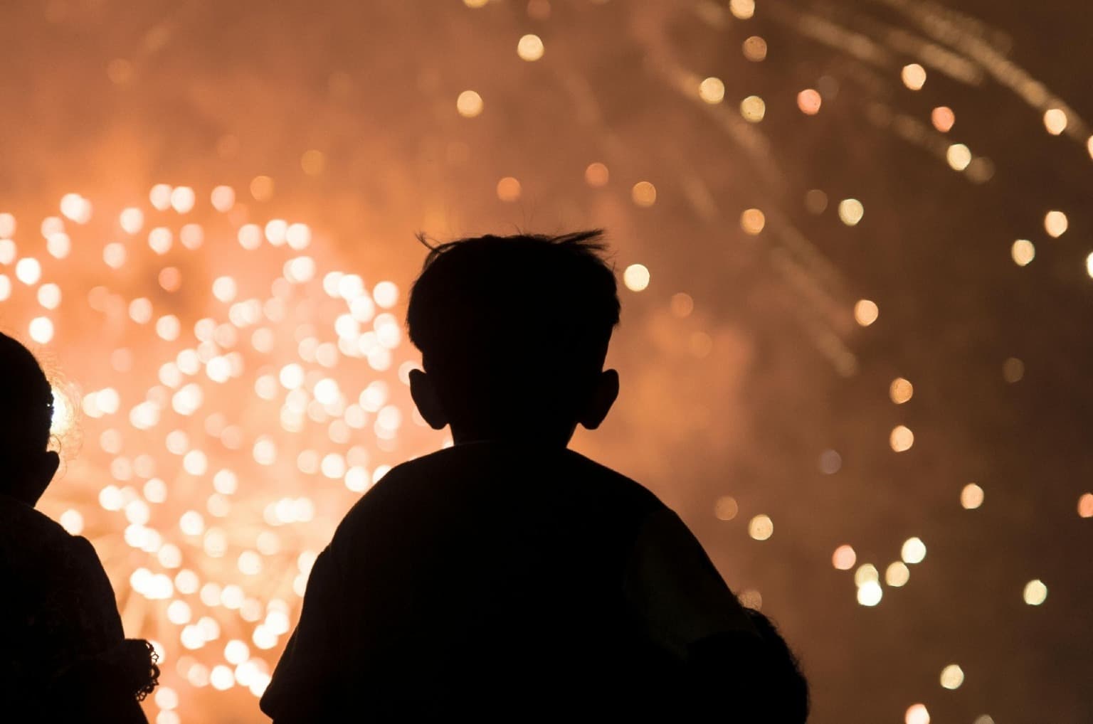 Uma criança a assistir o fogo de artifício da passagem de ano