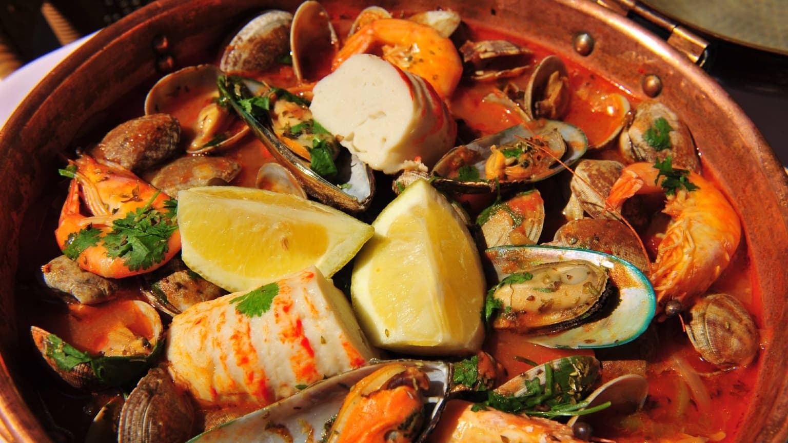 Tradicional cataplana de marisco do Algarve preparada com peixe, marisco e ervas aromáticas