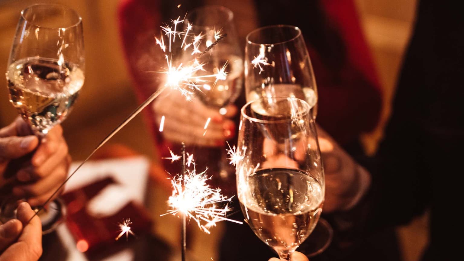 Amigos brindando com espumante e segurando fogos de artifício durante a celebração da véspera de Ano Novo no Porto