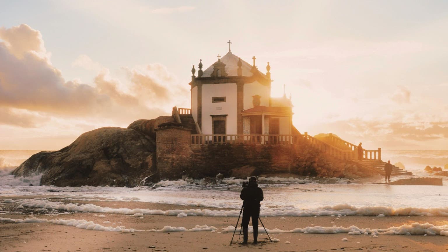 Imagen de la Playa de Miramar y la Capela do Senhor da Pedra al atardecer