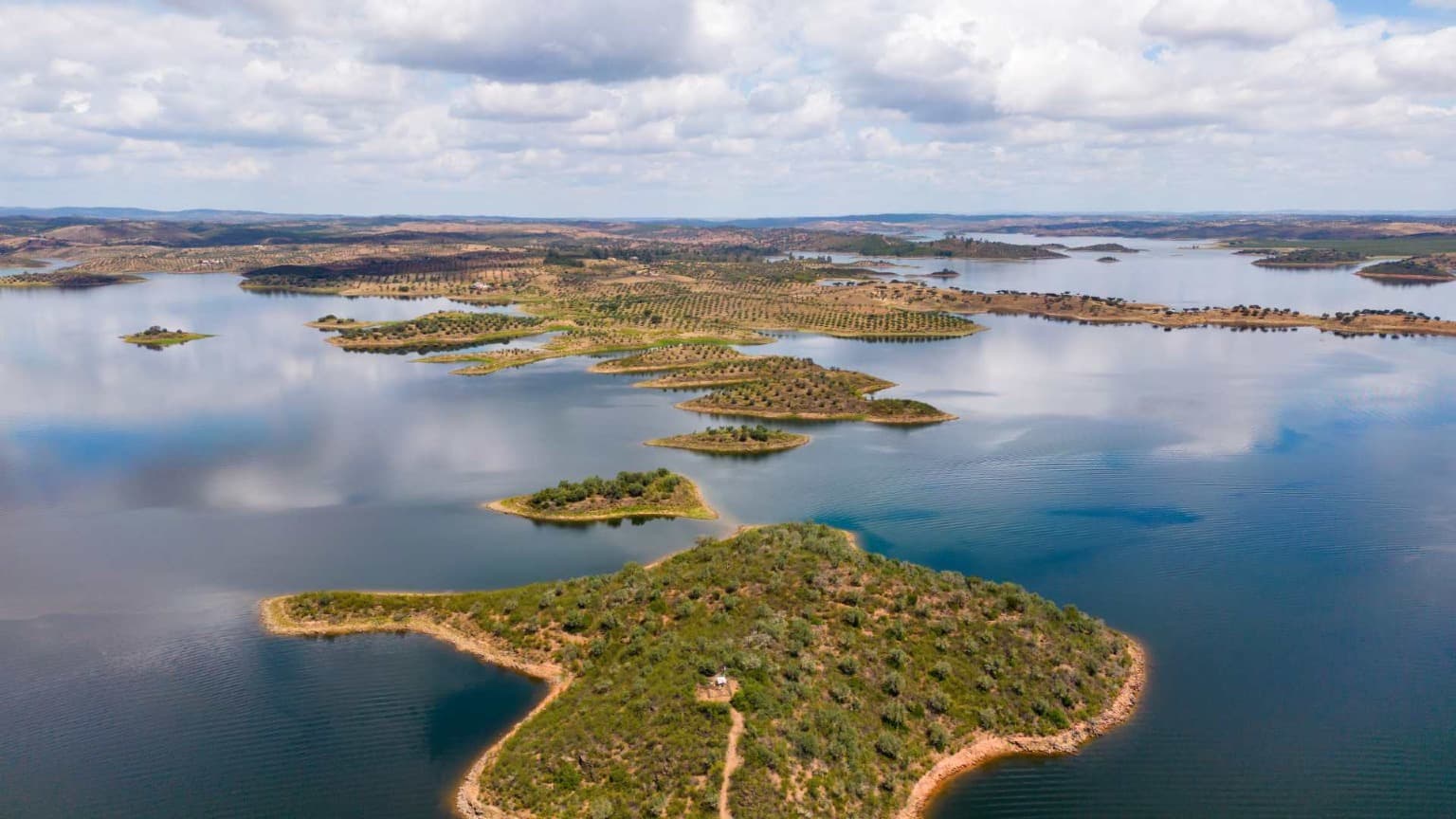 Vista aérea del lago Alqueva, en la que se aprecian islas, olivares y el paisaje circundante del Alentejo.