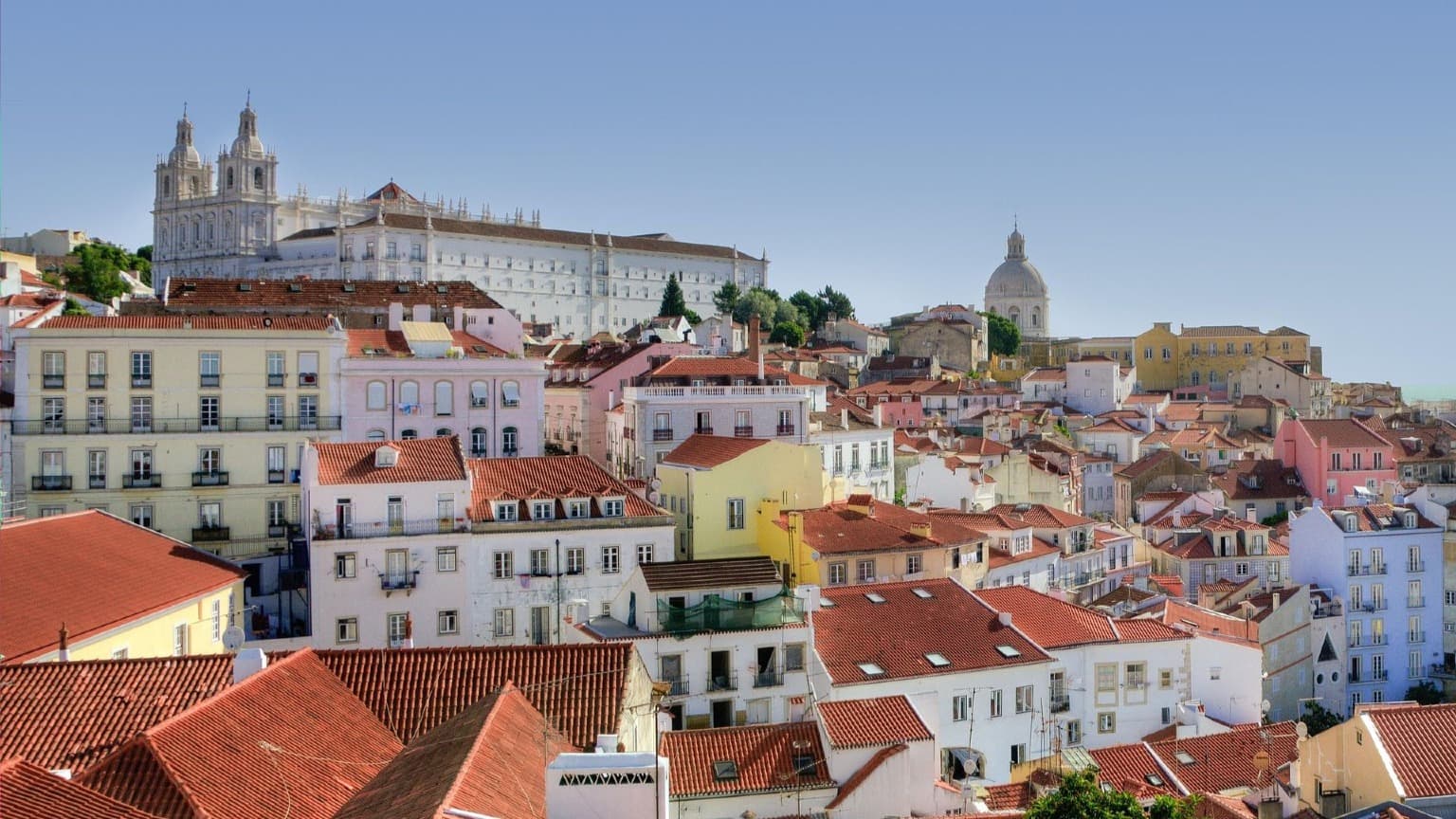 Colorful rooftops and historic houses of the Alfama district in Lisbon with the National Pantheon in the background
