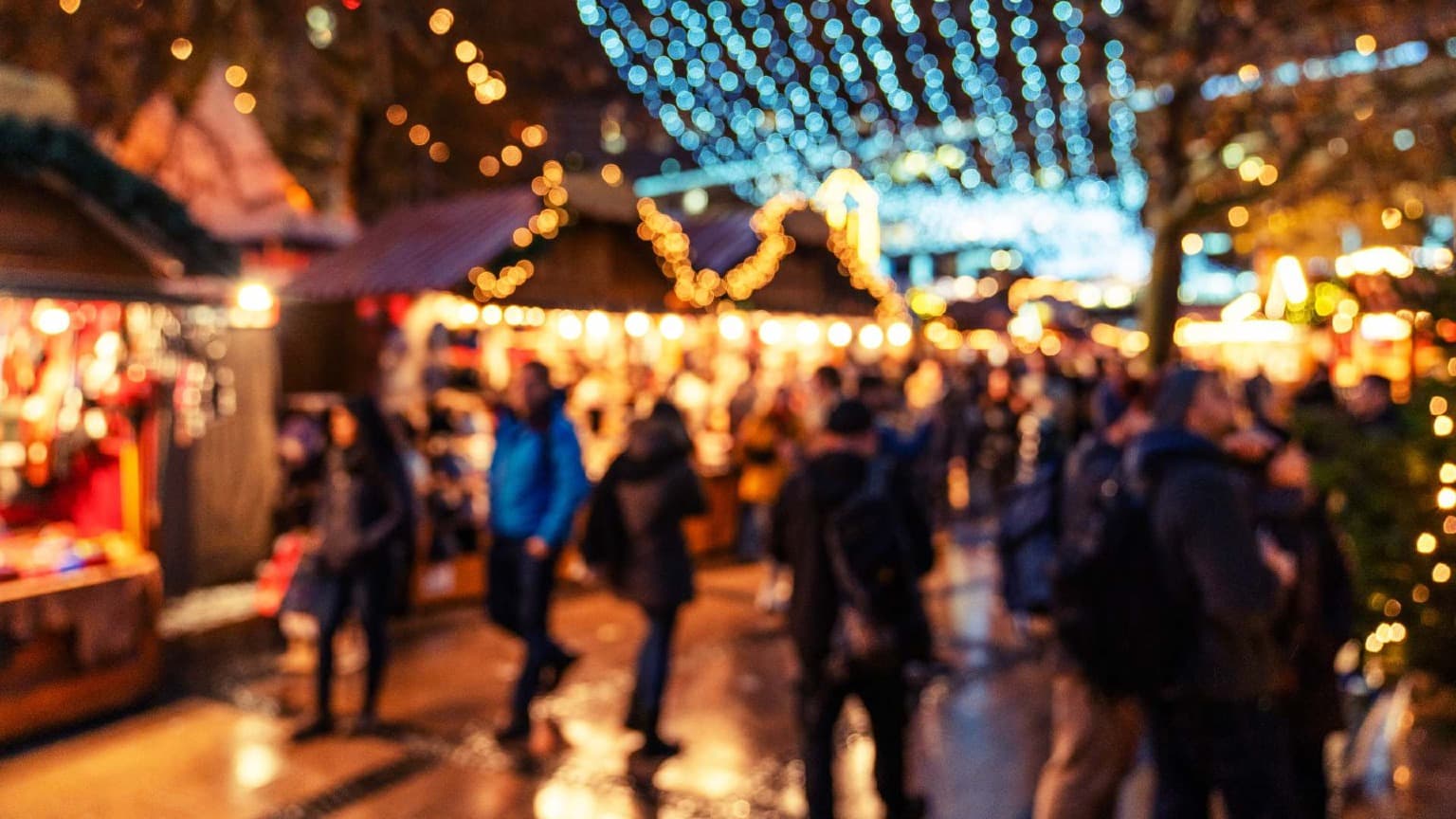 Multitud explorando el mercado navideño iluminado de Cordoaria en Oporto bajo las brillantes luces festivas.