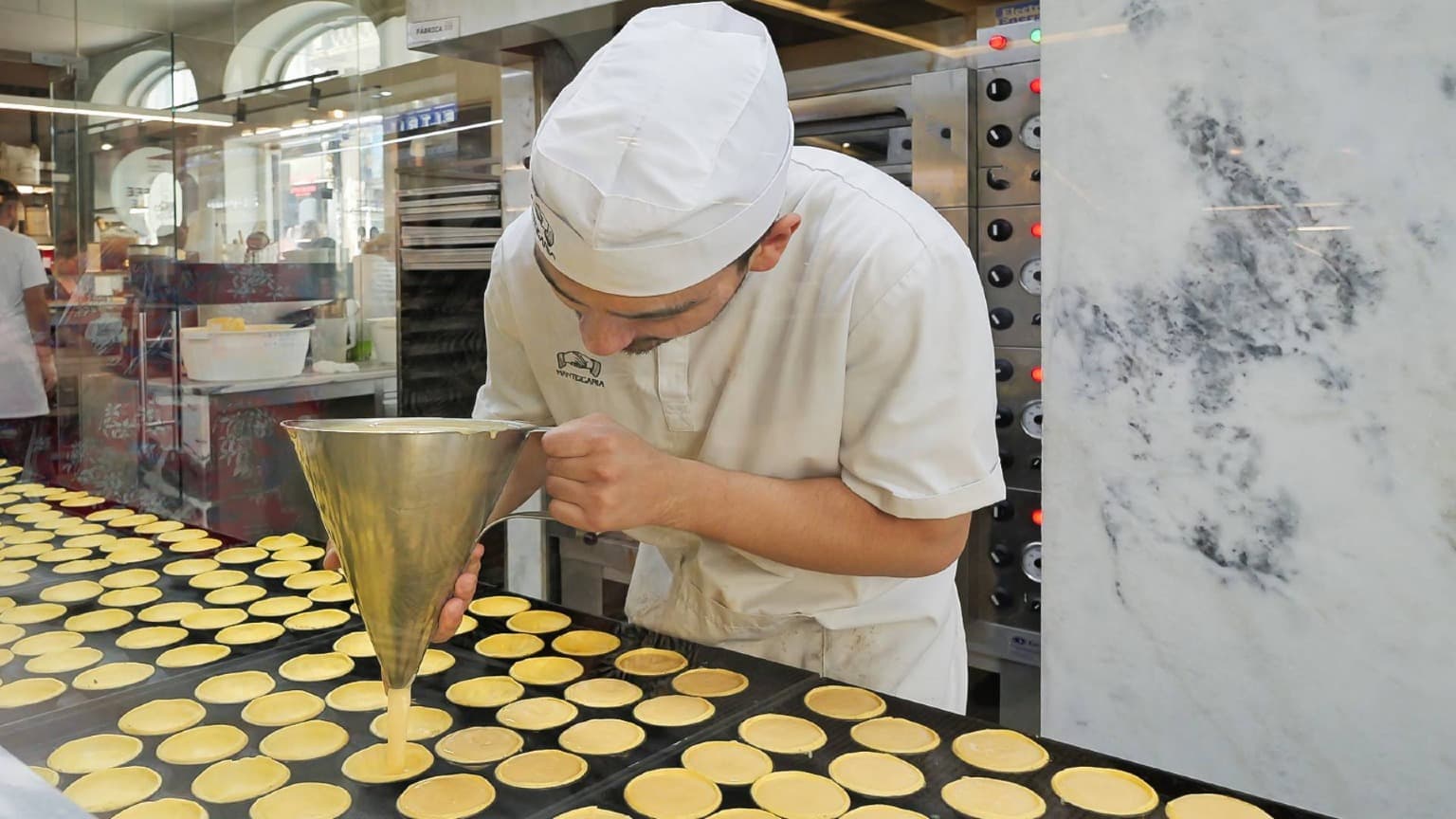 Pastéis de Nata acabados de fazer a serem preparados numa pastelaria tradicional portuguesa