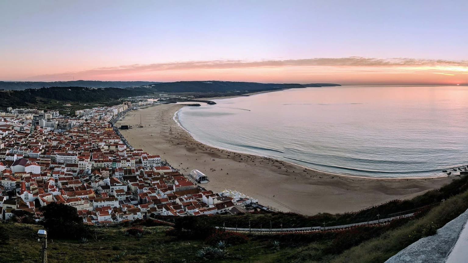 Vista panorámica de la puesta de sol sobre la playa de Nazaré y el casco antiguo tomada desde el mirador de Sítio durante el invierno.