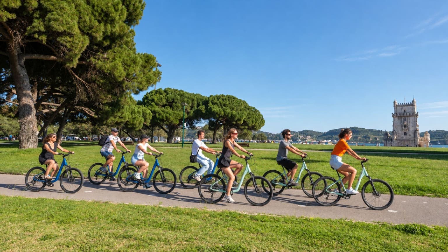 Groupe de cyclistes parcourant un espace vert au bord du fleuve près de la tour de Belém à Lisbonne