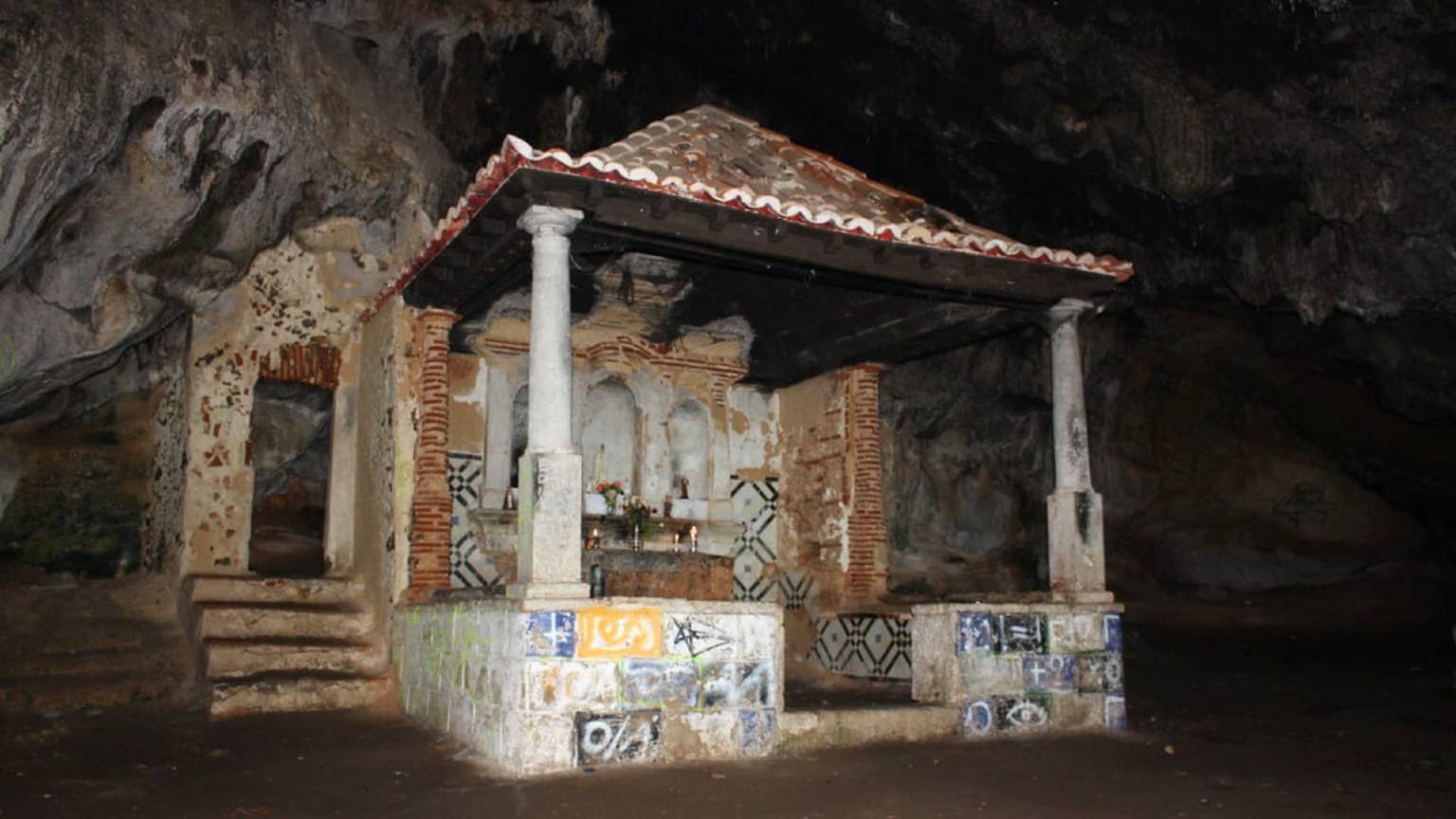 Intérieur de Lapa de Santa Margarida dans le parc naturel d'Arrábida, montrant une chapelle en pierre construite à l'intérieur d'une grotte en bord de mer.