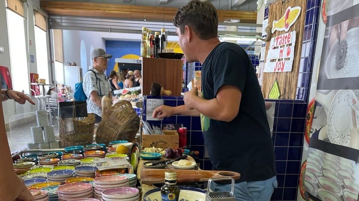 Vendedor local a apresentar cerâmica artesanal algarvia e azeite no mercado de Lagos