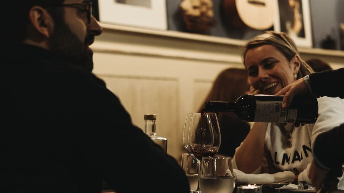 Pareja disfrutando de vino y del ambiente tradicional durante un espectáculo de Fado en Oporto