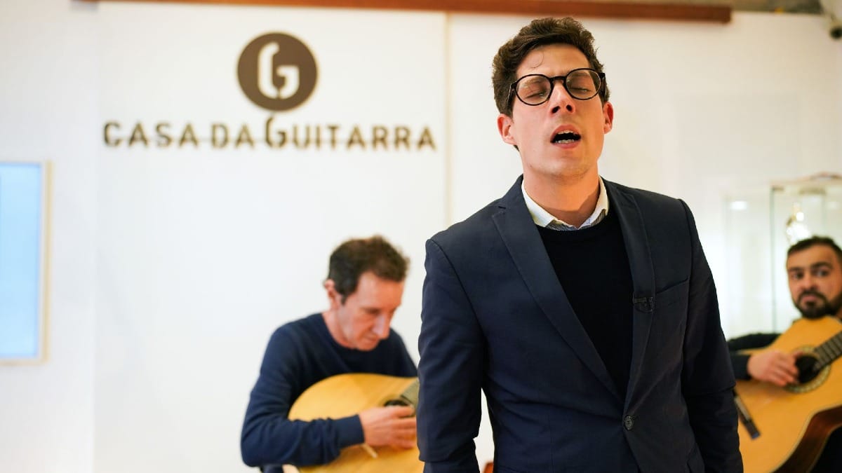 Male Fado singer performing live with guitarists at Casa da Guitarra in Porto