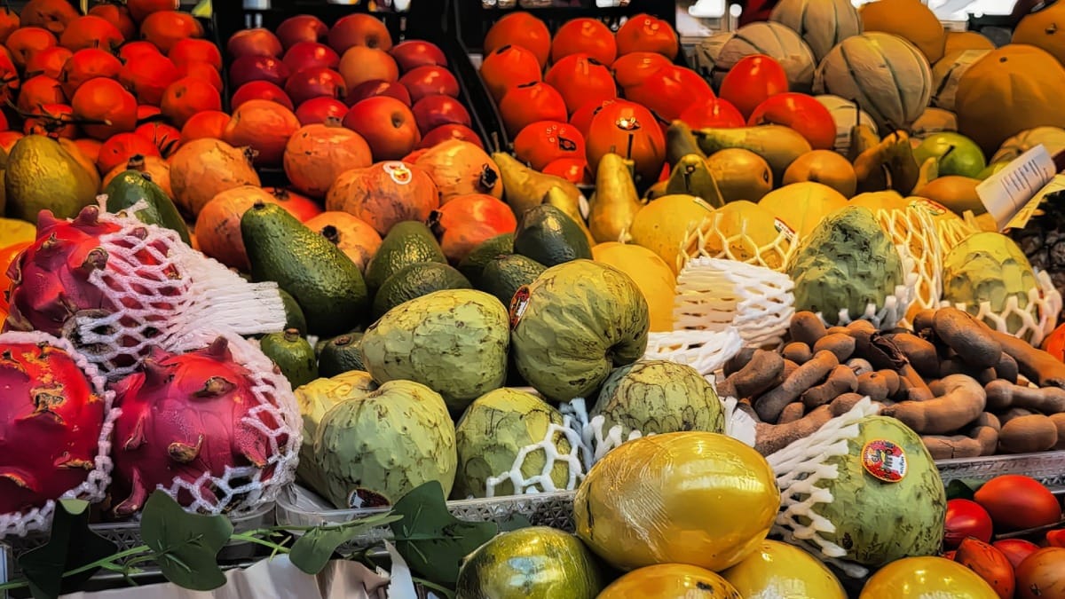 Frutas exóticas coloridas em exposição num mercado vibrante do Porto, uma paragem do food tour