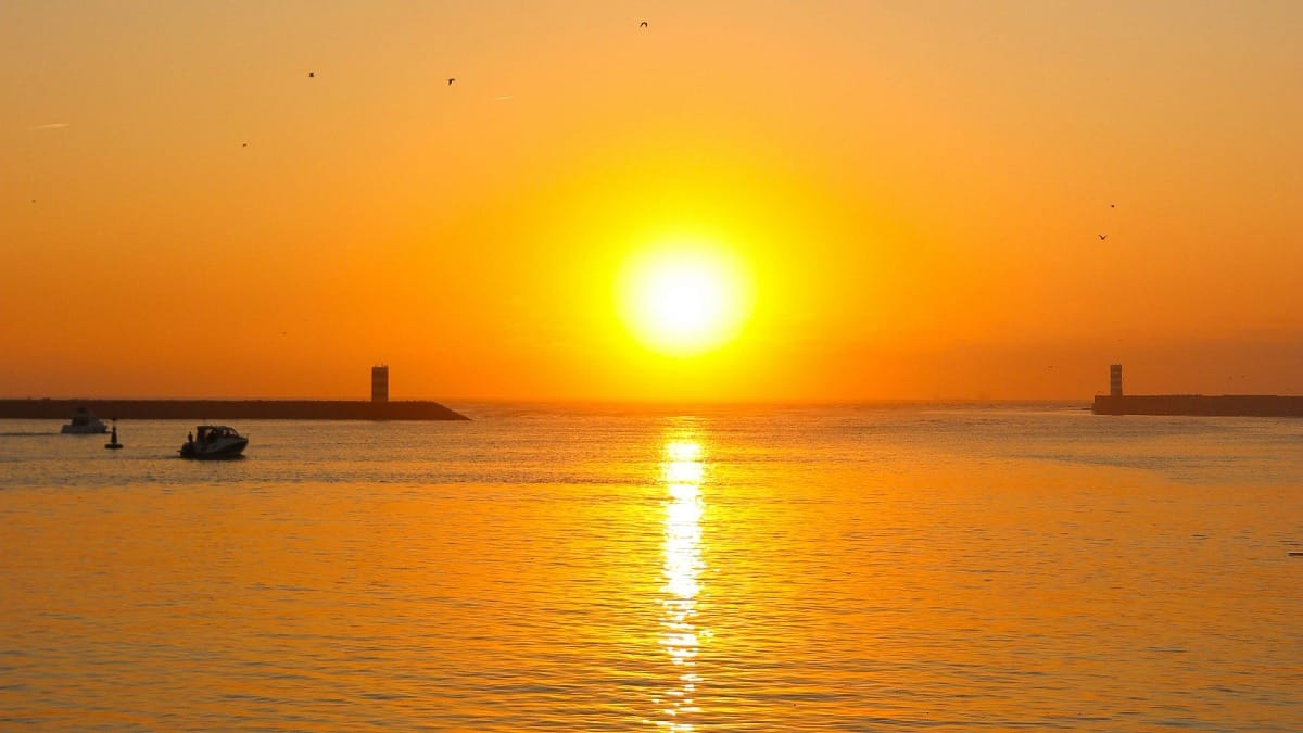 Coucher de soleil magique et orange à l'embouchure du fleuve Douro pendant une croisière privée au moment de l'heure dorée à Porto