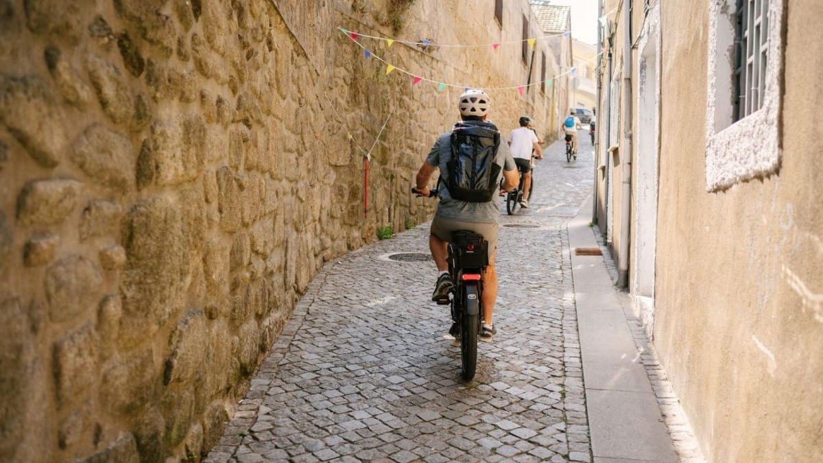 Groupe pédalant à vélo électrique à travers les rues historiques de Porto lors d'une visite guidée des points incontournables de la ville en e-bike
