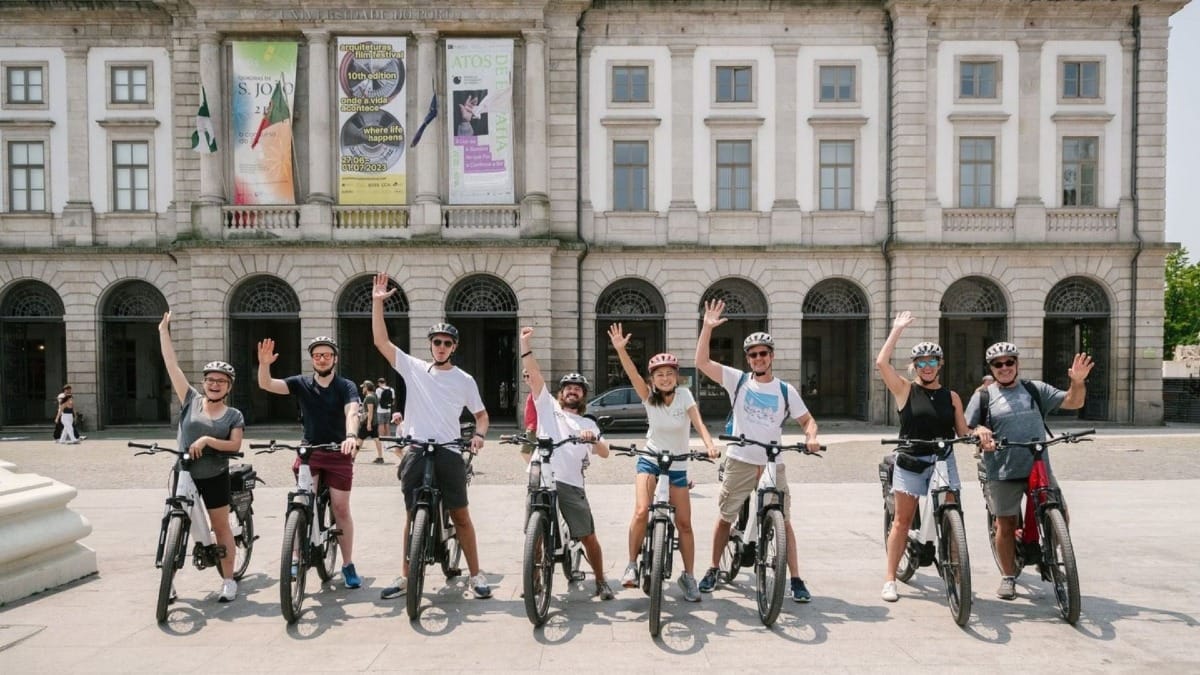 Group on an electric bike tour in Porto pausing for a photo in front of the historic University of Porto