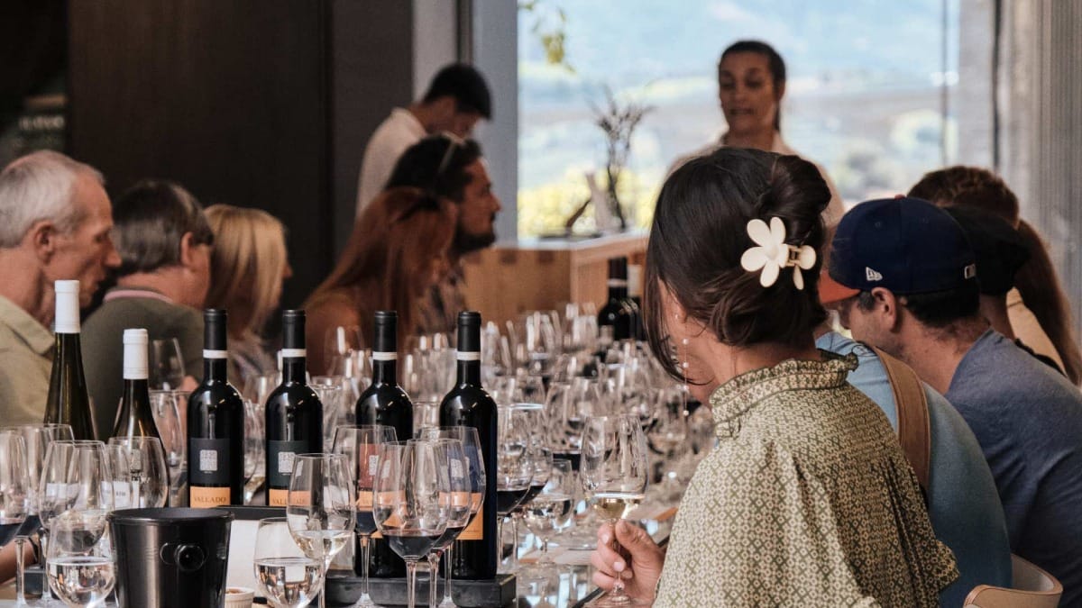 Invités participant à une dégustation guidée à Quinta do Vallado, avec une table dressée avec des vins Vallado et des verres