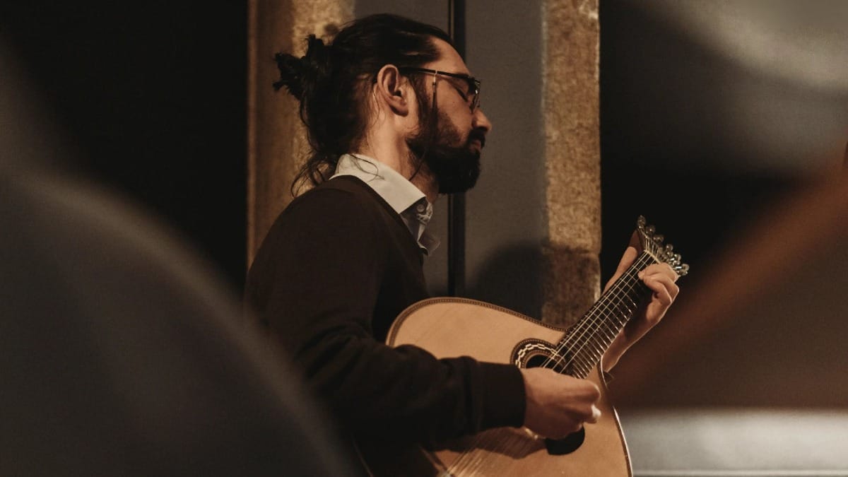 Guitariste portugais en pleine performance de Fado dans une salle chaleureuse à Porto