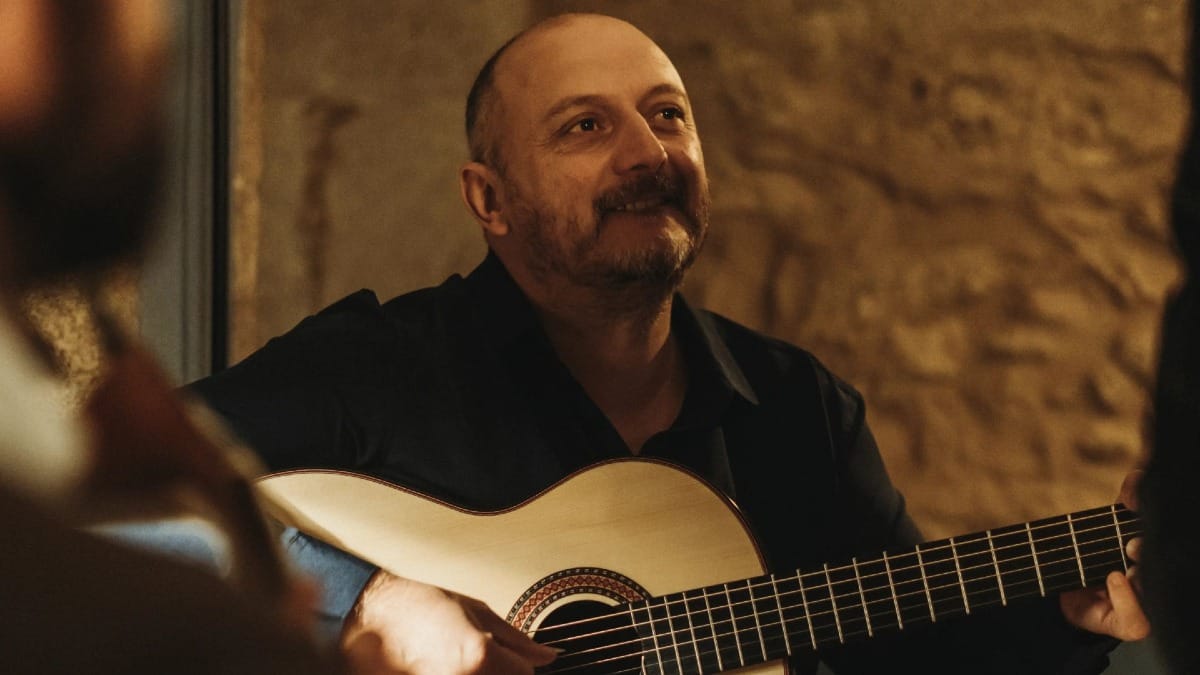Atmosphère intime avec un musicien souriant jouant de la guitare classique lors d’un concert de Fado à Porto