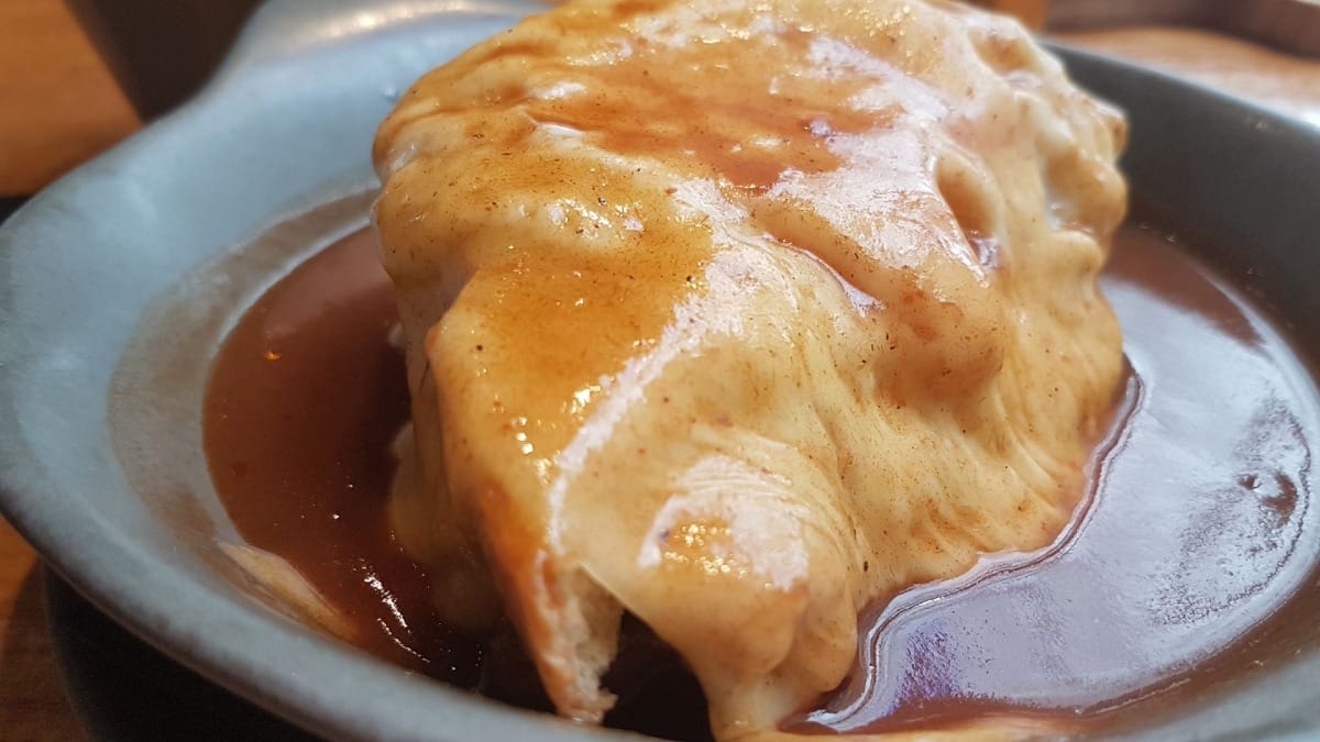 Close-up of a freshly made Francesinha covered in spicy sauce, a must-try Porto delicacy