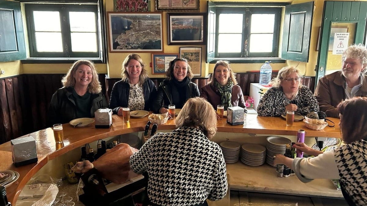 Visitantes sentados en la barra de una taberna rústica en Lagos, disfrutando de cerveza local