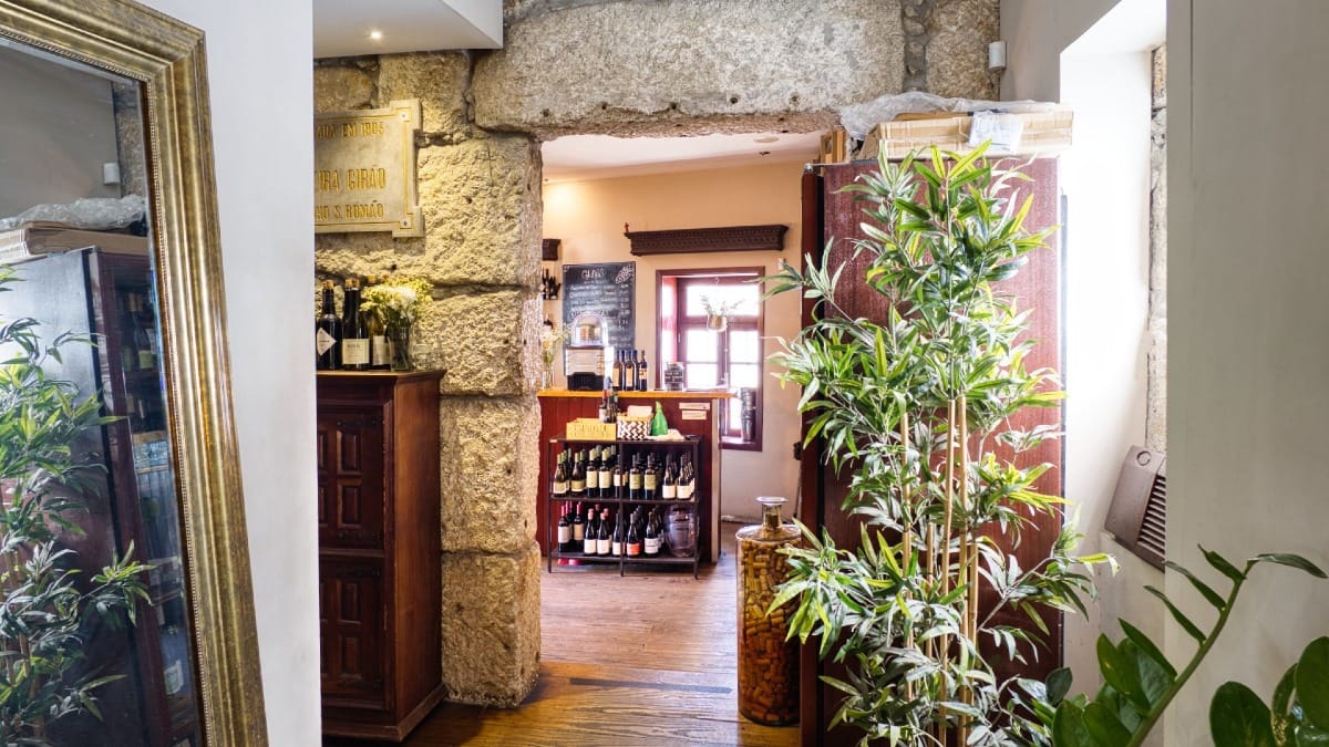 Interior acolhedor de bar de vinhos escondido no Porto com prateleiras de vinhos portugueses e decoração rústica